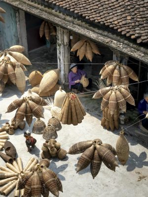 From above of people sitting and making bamboo fish traps while working on local bazaar in Vietnam in daylight